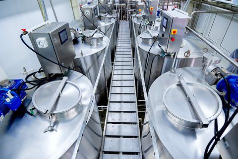 Stainless dairy processing plant interior, automated blending vessels and walkway