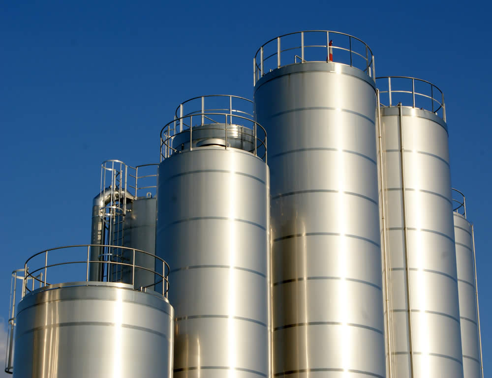 Stainless steel storage silos against a clear sky at an industrial site